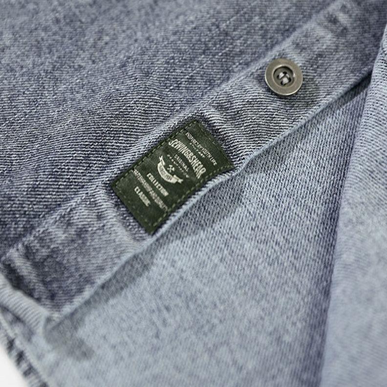 A close-up view of washed denim fabric with a visible button and a black clothing label featuring white text and a small emblem—perfect details for your favorite overshirt.