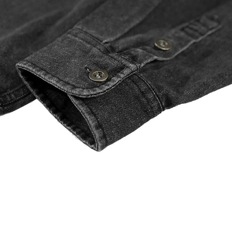 Close-up of the cuff of a black washed denim long-sleeve overshirt, featuring a buttoned closure and visible stitching detail.
