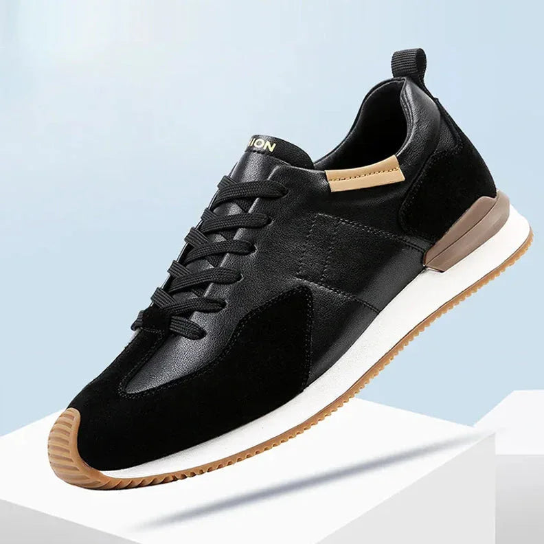 A stylish black sneaker with a white sole, brown accents on the heel and sole edge, and black laces, crafted from top-grain leather for added durability, displayed against a light blue and white background.