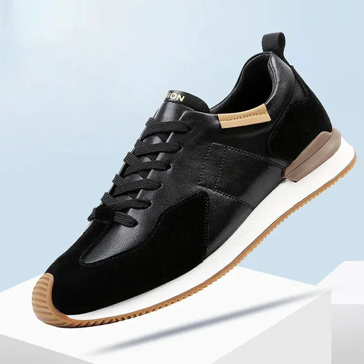 A stylish black sneaker with a white sole, brown accents on the heel and sole edge, and black laces, crafted from top-grain leather for added durability, displayed against a light blue and white background.