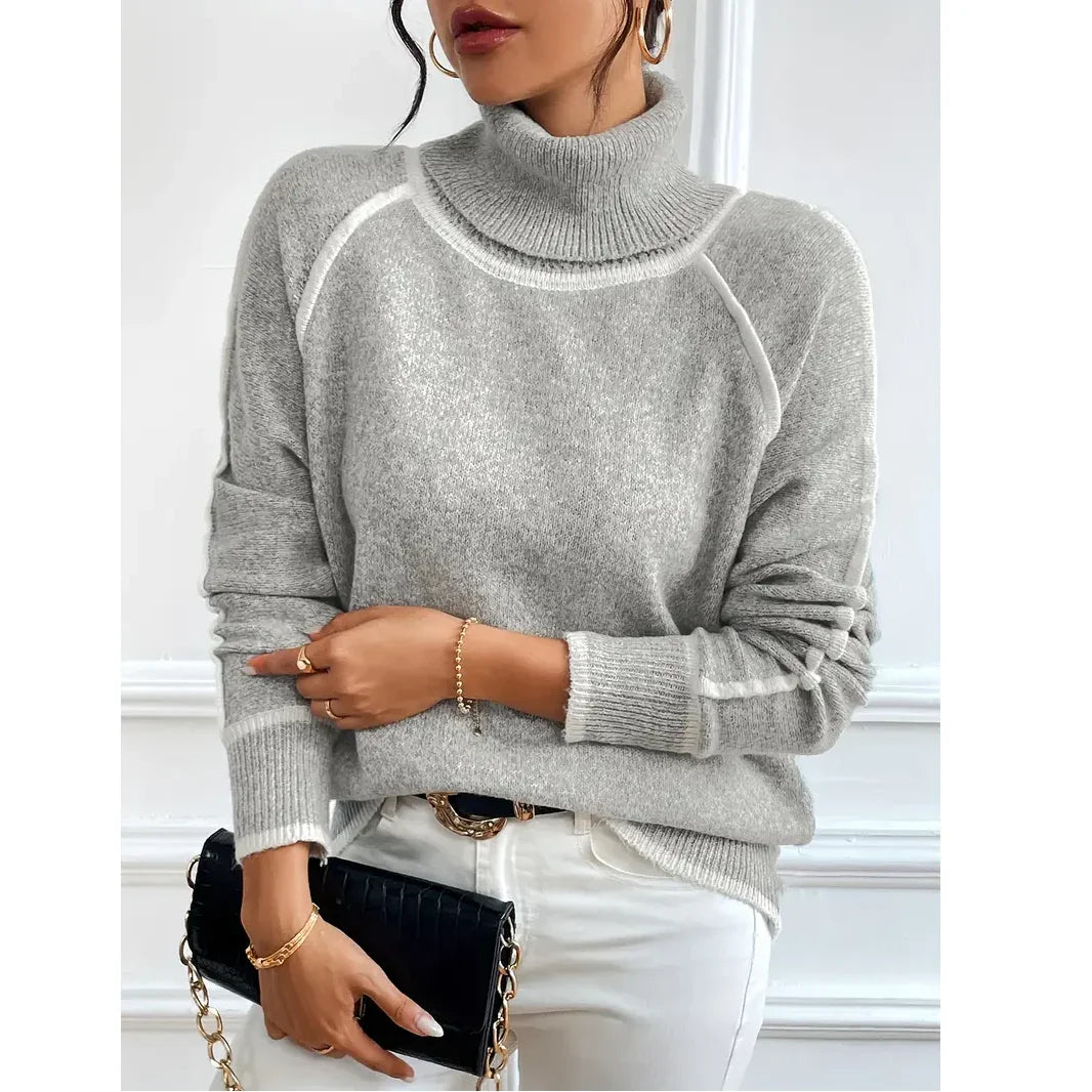 Woman wearing grey turtleneck sweater, white pants, and black clutch, Rovelli fashion
