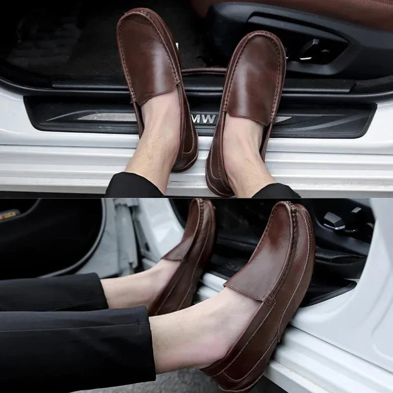 A person wearing genuine leather loafers with cushioned insoles and black pants sits in the open doorway of a white vehicle, resting their feet on the car’s door frame.