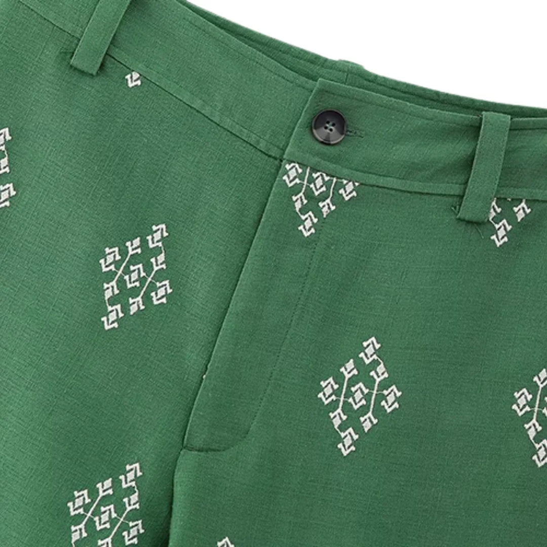 Boho chic pants featuring a white geometric embroidered pattern, black button waistband, belt loops, and a side pocket. These linen trousers have a slightly textured look for added style.