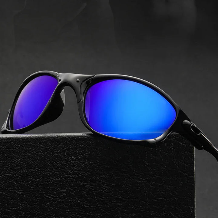 A pair of black cycling sunglasses with a rectangular frame and reflective blue lenses rests on a textured black surface against a dark background, offering stylish UV400 protection.