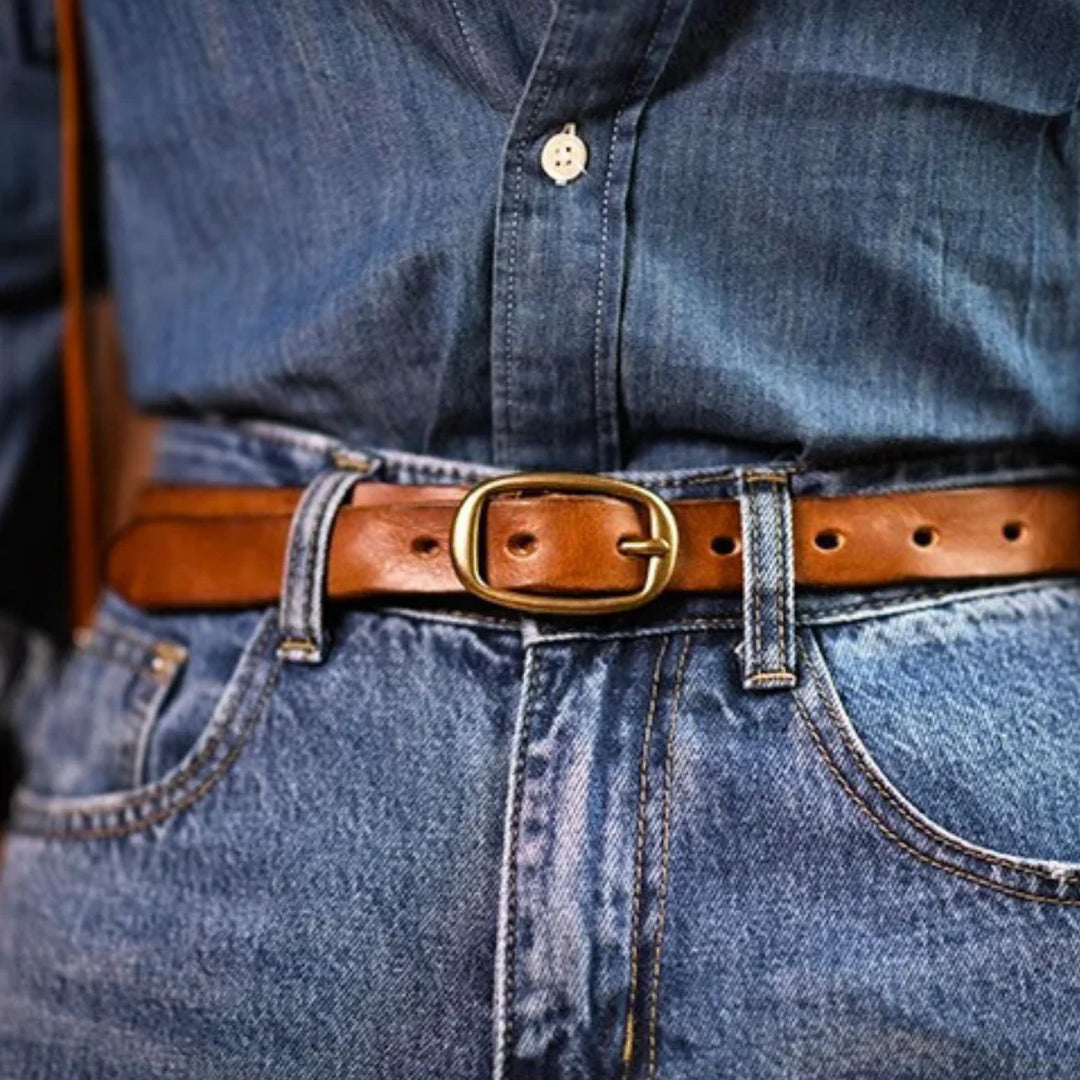 A close-up of a person wearing a blue denim shirt tucked into blue jeans, secured with a genuine leather belt featuring a gold buckle for a touch of Southern style.
