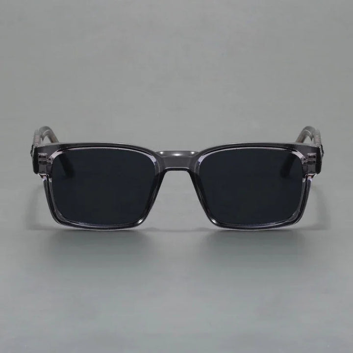 A pair of rectangular, black sunglasses with thick, translucent gray frames and modern design, offering UV400 protection, displayed against a plain gray background.