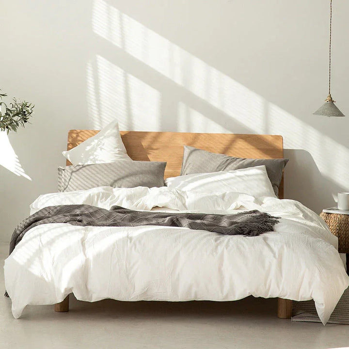 Modern bedroom with wooden bed frame, white bedding, gray blanket, sunlight, Rovelli home style