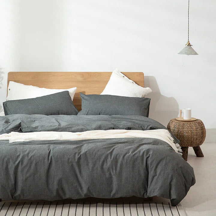 Rovelli modern bedroom with grey bedding, wooden headboard, and woven nightstand