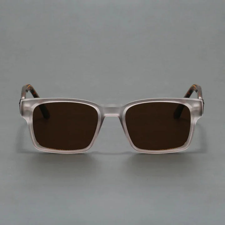 A pair of square, transparent-framed sunglasses with a modern design and dark tinted lenses offering UV400 protection, displayed against a plain gray background.
