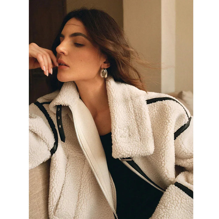 Woman in cozy white shearling jacket by Rovelli, indoors, wearing statement earrings