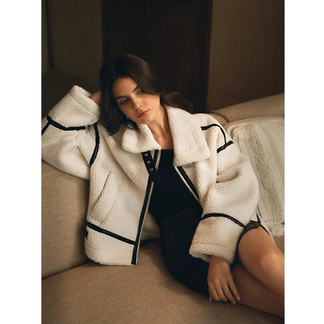 Woman on sofa wearing a white sherpa jacket with black trim, Rovelli fashion style