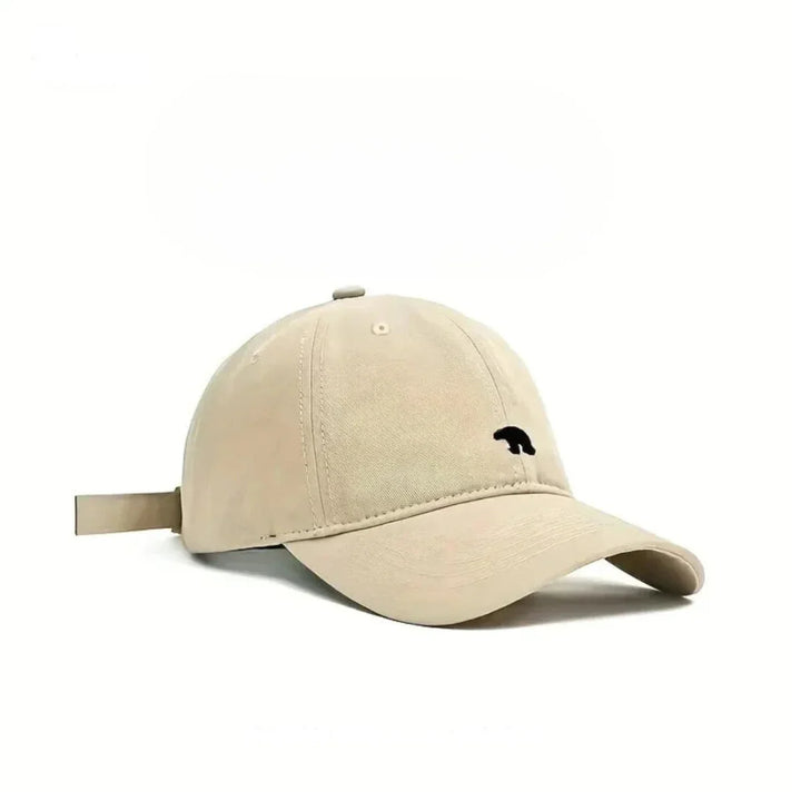 A beige baseball cap made from premium cotton with a small black bear silhouette embroidered on the front, shown against a plain white background.