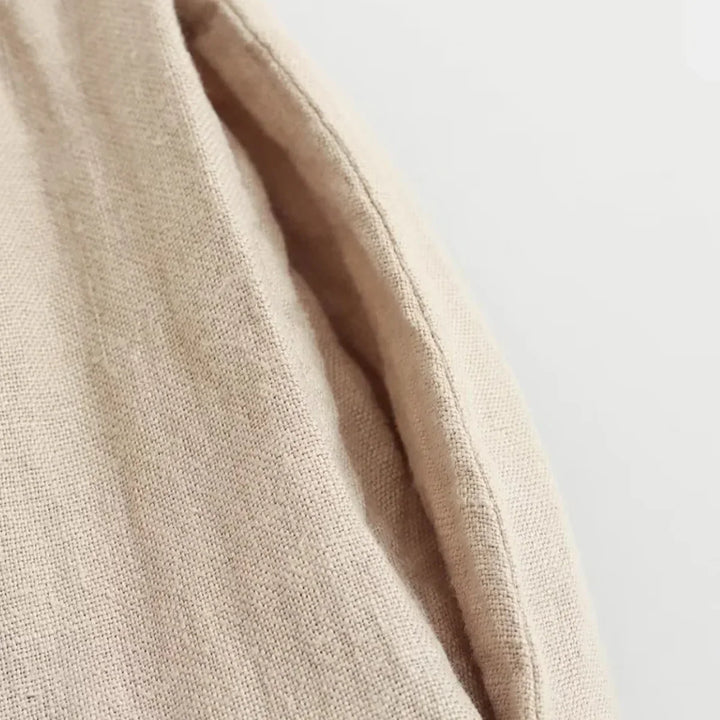 Close-up of beige linen fabric with a visible seam and textured weave, perfect for chic halter collar designs and effortless summer style, shown against a plain light background.