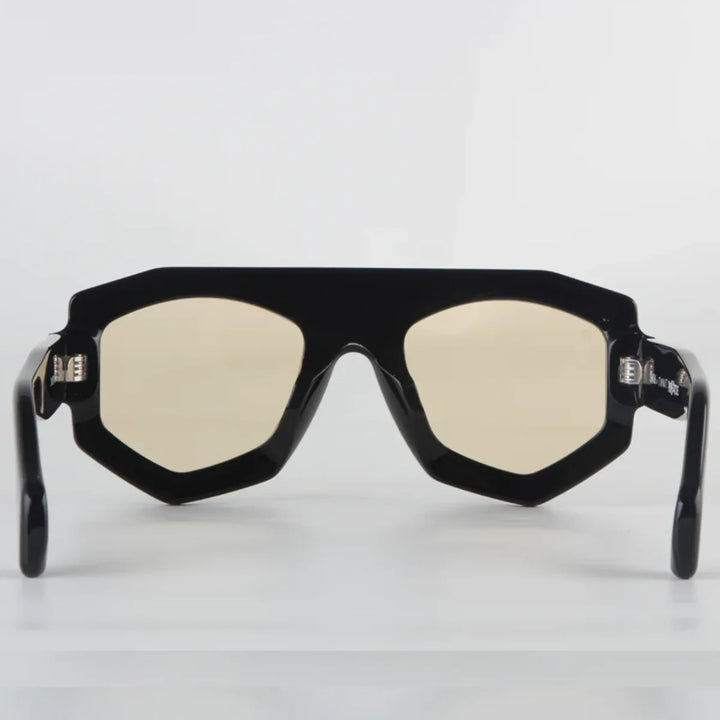 A pair of black, geometric-frame sunglasses crafted from acetate with slightly yellow-tinted lenses and UV400 protection, shown from the front on a plain white background.