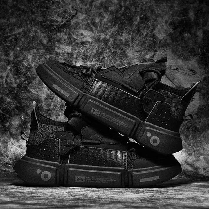 A pair of black Extreme VS7 Sneakers are stacked on top of each other against a textured, grunge-style background. These streetwear sneakers feature thick soles, mesh panels, and geometric accents for a bold, futuristic look.