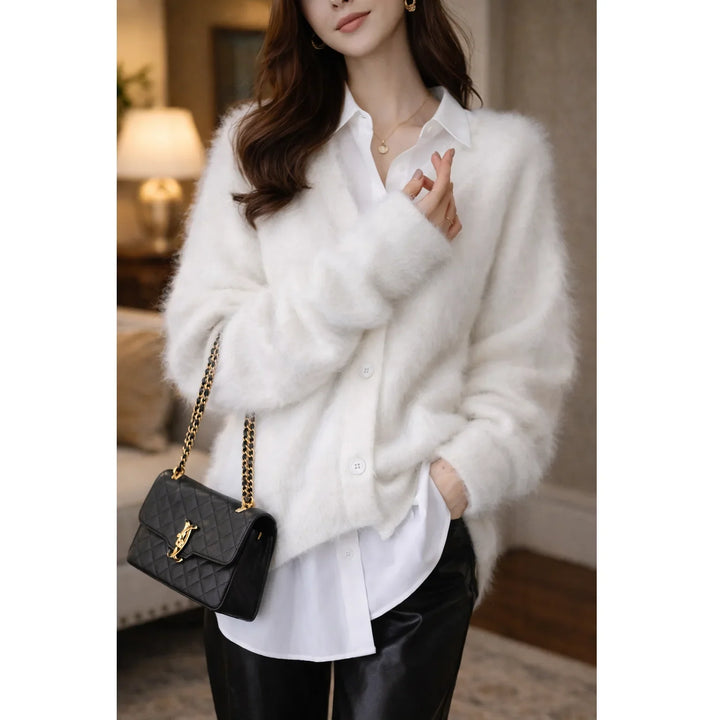Woman in chic white fuzzy cardigan, white shirt, black leather pants, holding black chain purse, Rovelli style