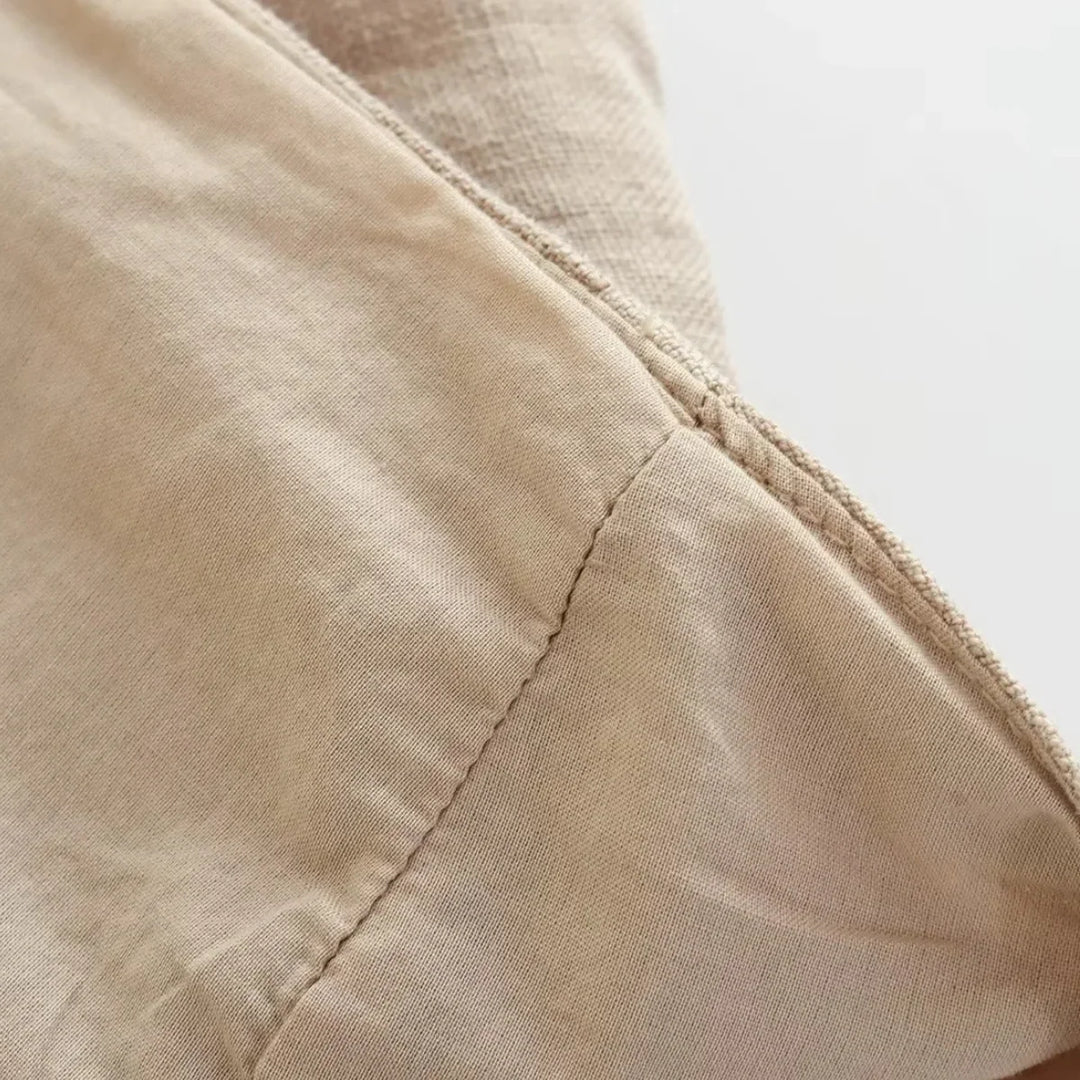 Close-up of light beige fabric with a visible seam, showing the texture and stitching detail. Perfect for wide-leg pants, the material appears soft and slightly wrinkled, with natural lighting highlighting its surface.