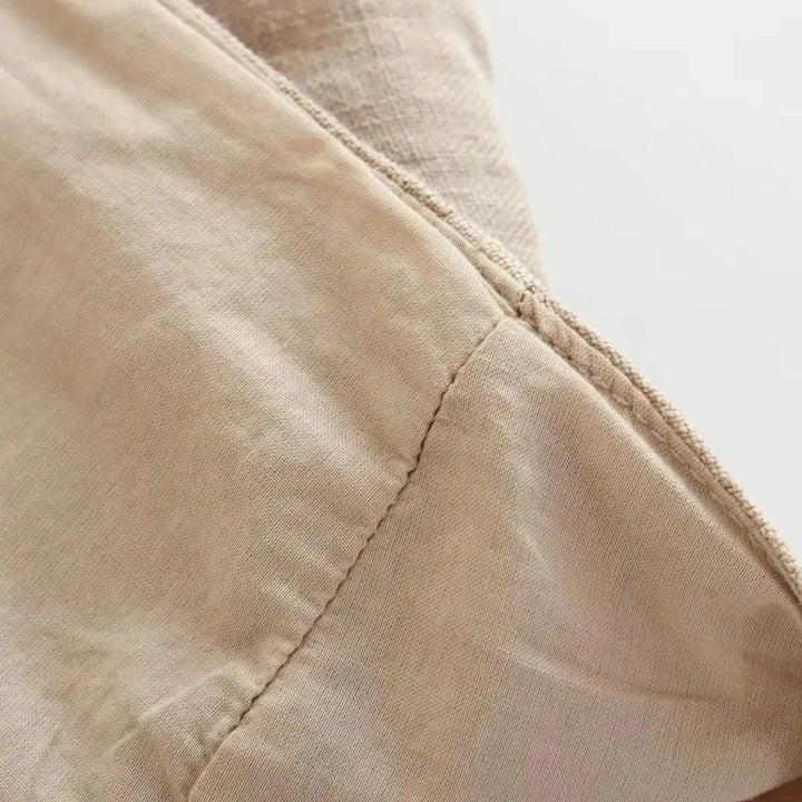 Close-up of light beige fabric with a visible seam, showing the texture and stitching detail. Perfect for wide-leg pants, the material appears soft and slightly wrinkled, with natural lighting highlighting its surface.