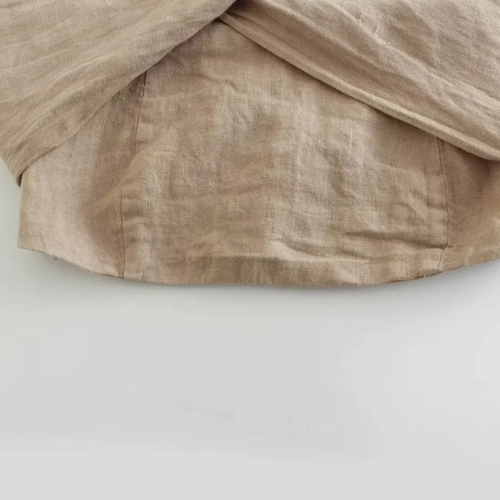 A close-up of a beige linen fabric with visible texture and stitching, draped in soft folds over a light surface—perfect for summer style essentials like chic halter collars or breezy wide-leg pants.