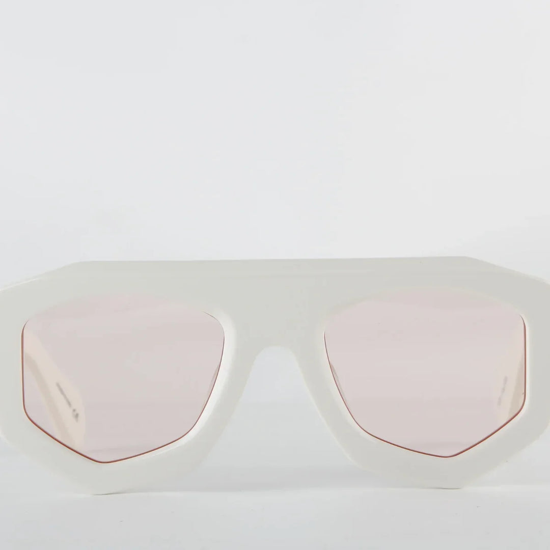 White oversized sunglasses with a thick geometric acetate frame and light pink tinted lenses, offering UV400 protection. Displayed against a plain white background.