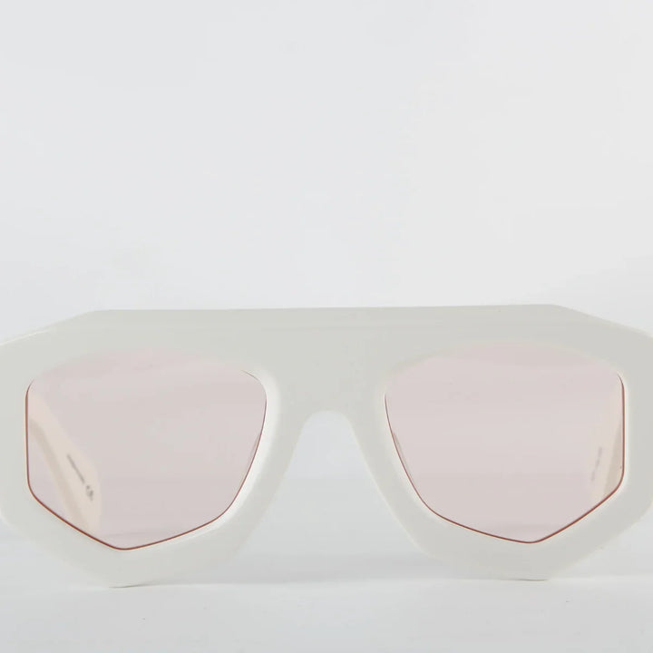White oversized sunglasses with a thick geometric acetate frame and light pink tinted lenses, offering UV400 protection. Displayed against a plain white background.