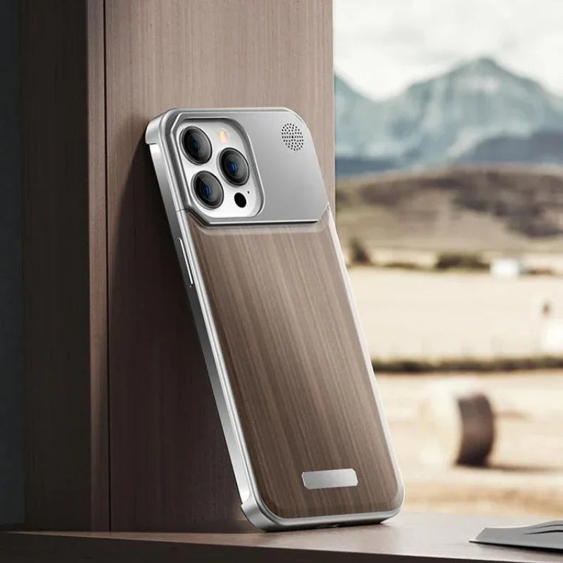 A smartphone with a stylish wood phone case and metallic accents rests upright against a wooden surface. Mountains and fields are blurred in the background, viewed through a window.
