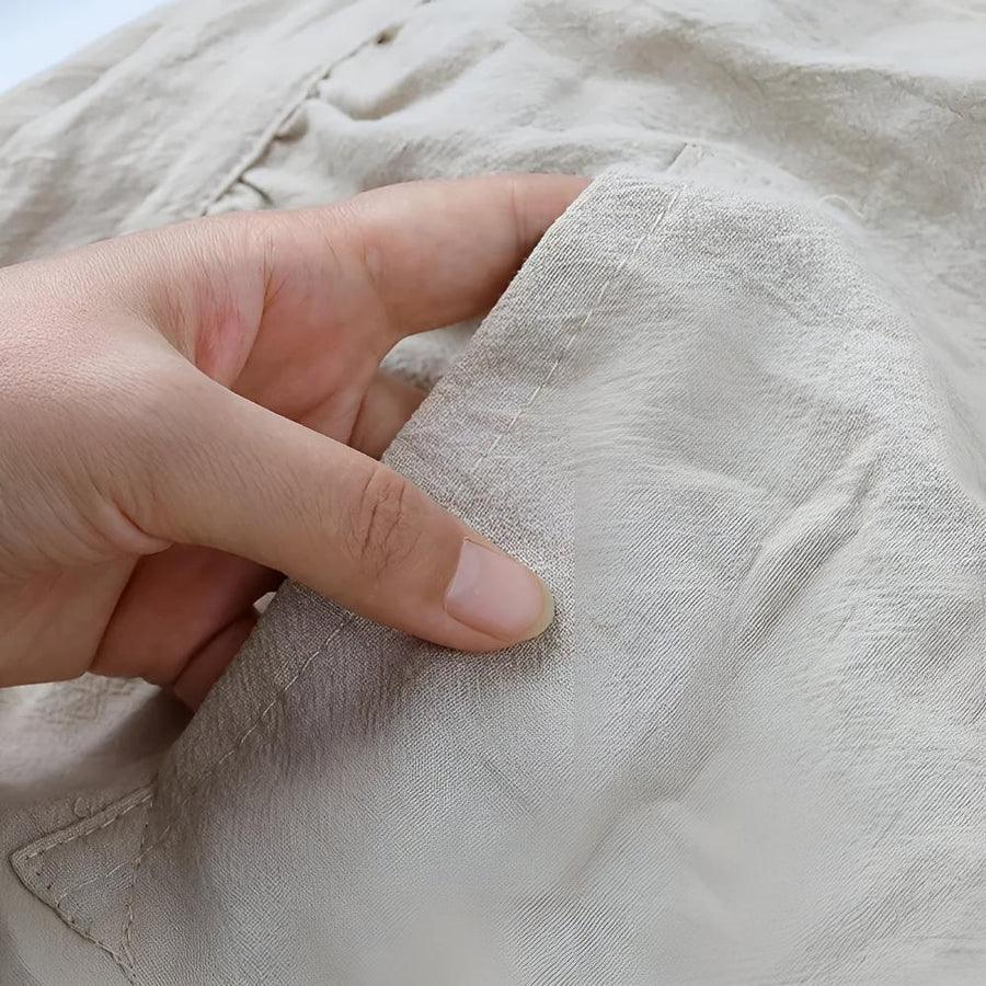 Hand holding soft beige Rovelli fabric close-up showing texture and stitching