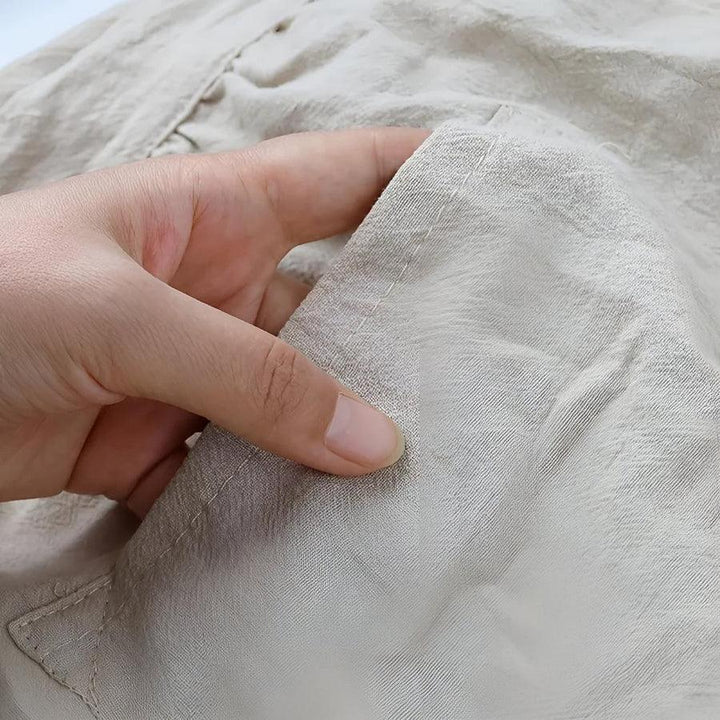 Hand holding soft beige Rovelli fabric close-up showing texture and stitching