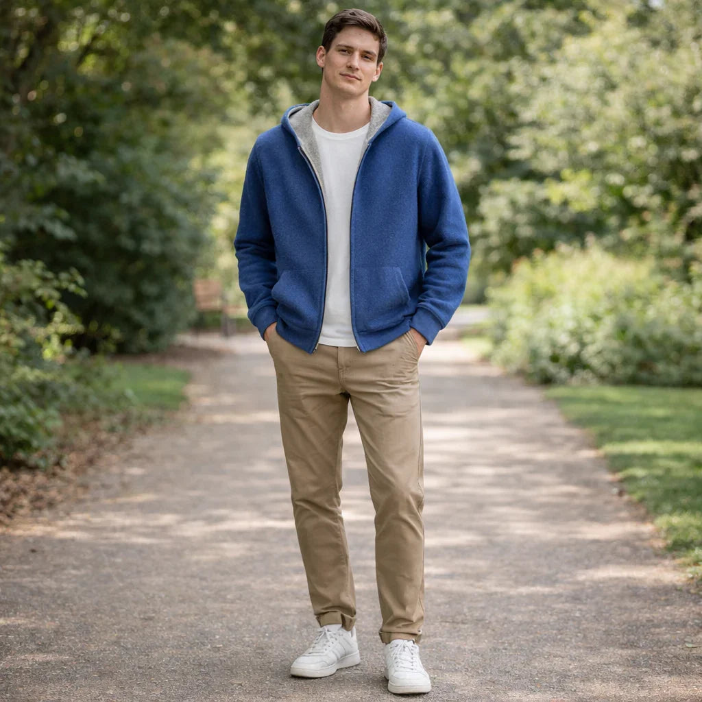 Man in casual Rovelli blue hoodie and khaki pants walking in a green park