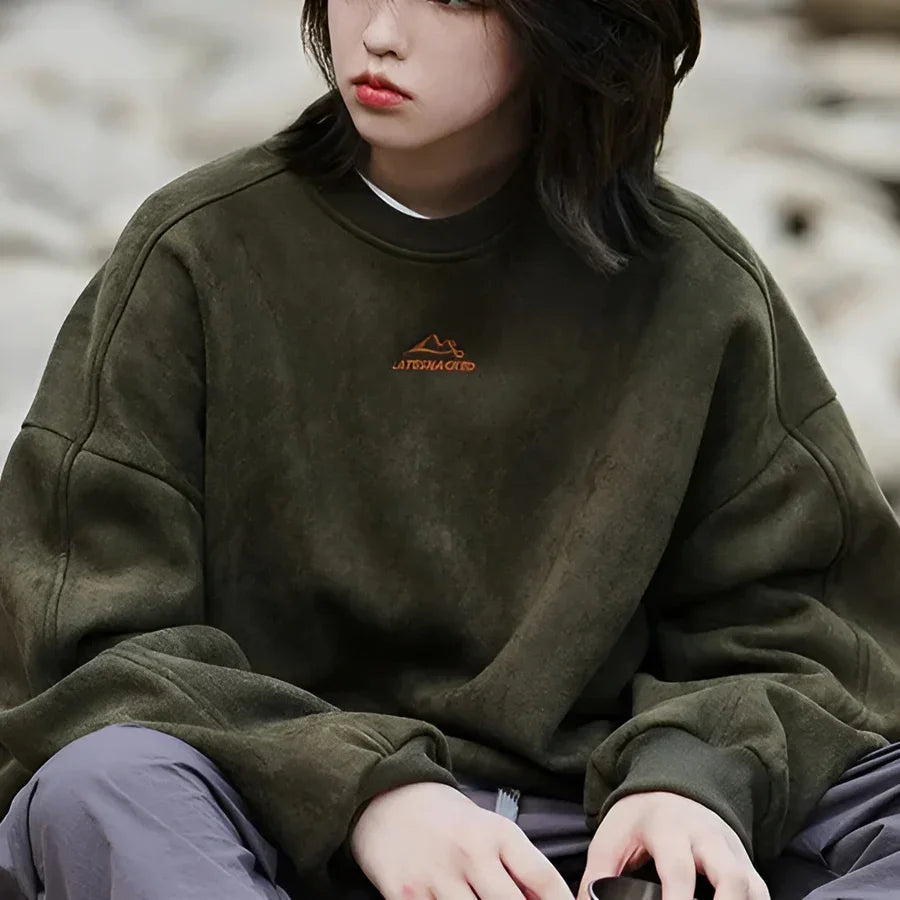 Person wearing oversized olive green Rovelli sweatshirt with embroidered mountain logo outdoors