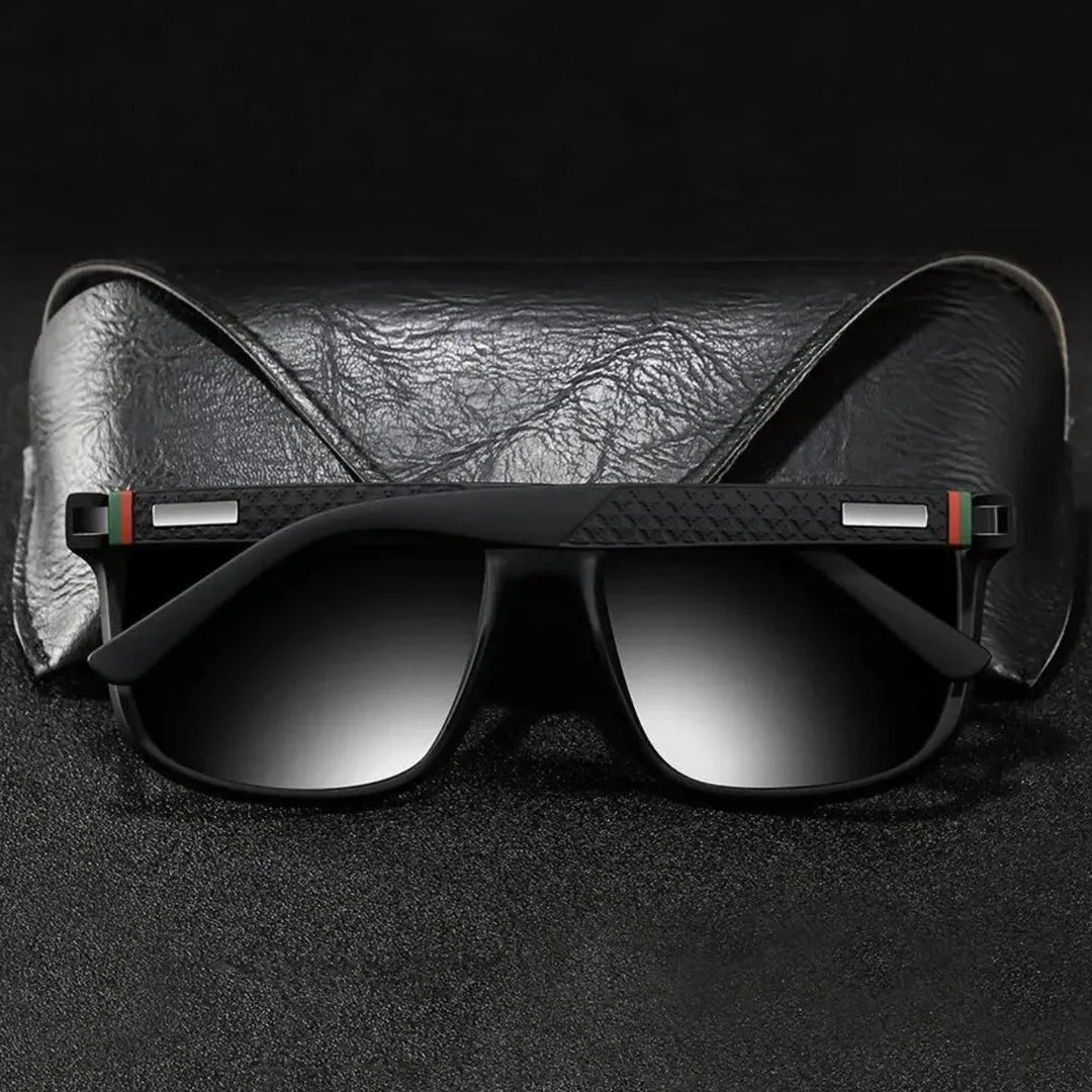 A pair of stylish UV400 sunglasses with gradient lenses rest in front of a black textured leather case, set against a dark background.