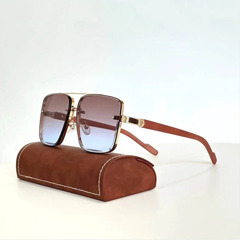 Stylish vintage sunglasses with brown gradient lenses, gold rims, and wooden arms rest on a brown leather case with white stitching, set against a plain white background.