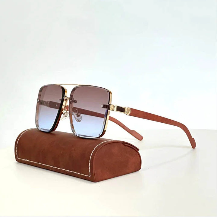 Stylish vintage sunglasses with brown gradient lenses, gold rims, and wooden arms rest on a brown leather case with white stitching, set against a plain white background.
