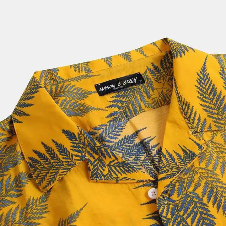 A yellow cotton shirt with a classic design, featuring blue fern leaf patterns. The brand label inside the collar reads MASON & BIRCH. The shirt is buttoned and displayed against a plain background—ideal for a casual brunch.