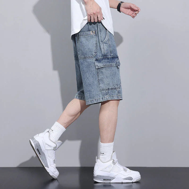 A person wearing a white t-shirt, mens denim shorts with an elastic waist, white crew socks, and white sneakers stands in profile against a plain gray background.