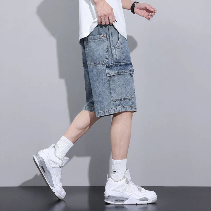 A person wearing a white t-shirt, mens denim shorts with an elastic waist, white crew socks, and white sneakers stands in profile against a plain gray background.