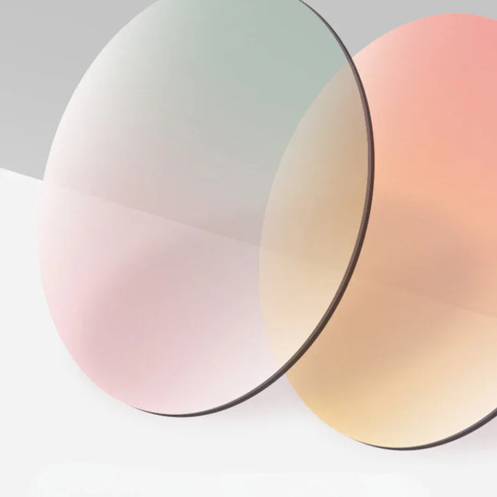 Two thin, round optical lenses with a slight tint—one with a pinkish hue, the other with a yellowish tint—overlap against a light gradient background, showcasing a trend-forward look.