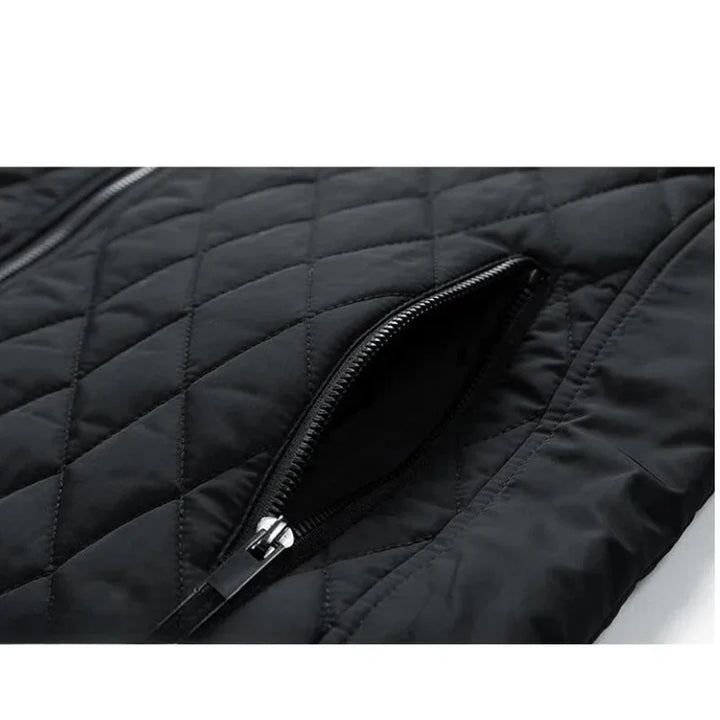 Close-up of a black quilted slim-fit jacket featuring a zippered pocket. The zipper is partially open, revealing the inner lining, and the diamond stitching pattern highlights its wind-resistant fabric.