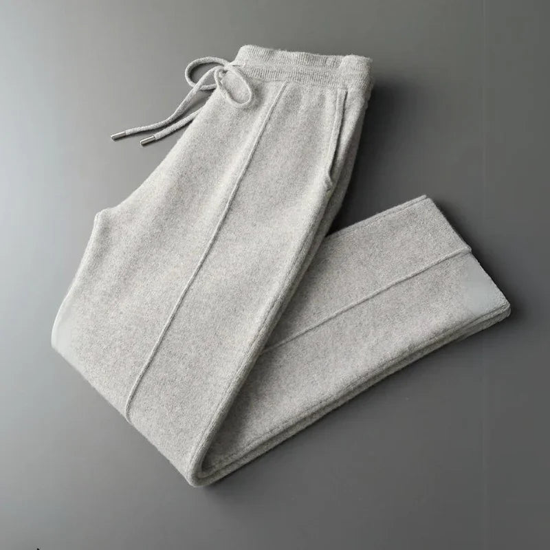 Light gray, comfortable pants with an elastic waistband and drawstring, folded neatly on a flat, dark gray surface.