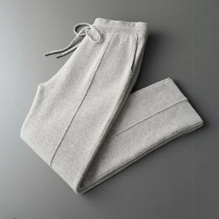 Light gray, comfortable pants with an elastic waistband and drawstring, folded neatly on a flat, dark gray surface.
