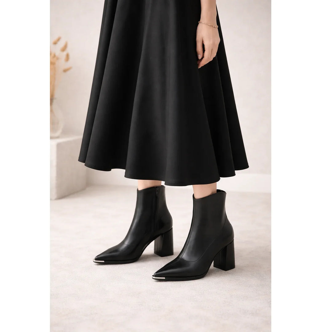 Woman wearing black heeled ankle boots and a black midi skirt, Rovelli fashion style