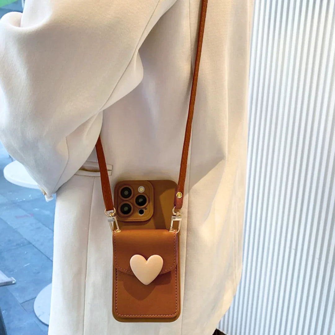 A person wearing a cream-colored coat carries a small brown phone pouch with a heart-shaped clasp and crossbody strap, partially open to reveal a smartphone inside.