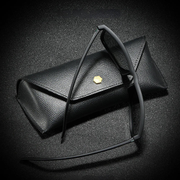 A pair of black-rimmed eyeglasses rests against a textured black eyeglass case with a small gold hexagonal emblem, all set on a black, slightly sparkly surface—perfect for storing your stylish sunglasses.