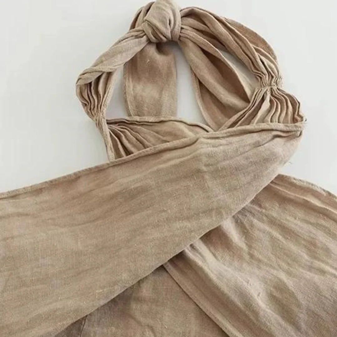 A beige linen scarf with a soft texture, loosely knotted at the top and laid out flat with the ends crossed, adds a touch of chic summer style—perfect for pairing with wide-leg pants on a light background.