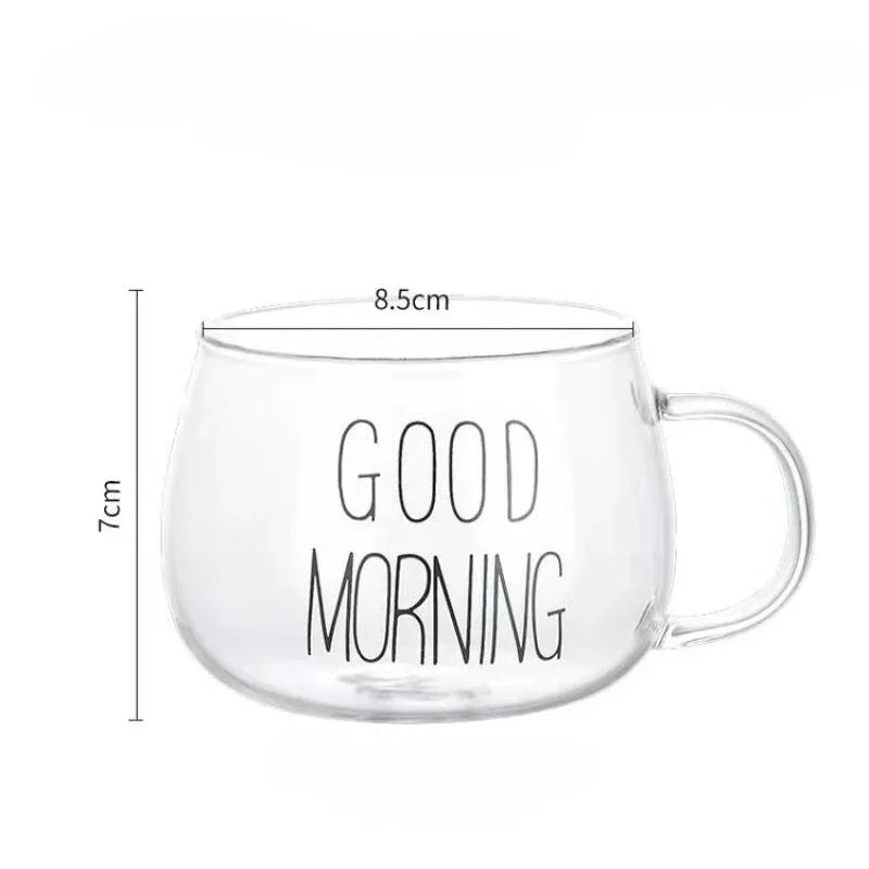 A clear glass mug with an ergonomic handle and GOOD MORNING written in black letters. Made from heat-resistant glass, the mug measures 8.5 cm in diameter and 7 cm in height, with a handle on the right side.