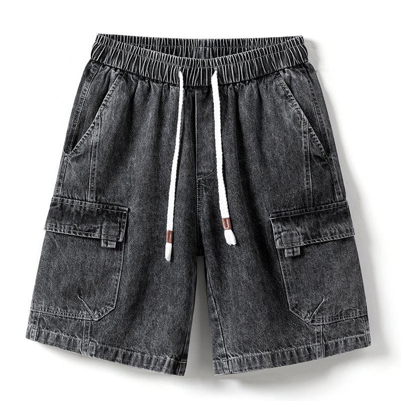 A pair of mens denim shorts in black with an elastic waist, white drawstring, side pockets, and flap pockets on each leg—laid flat on a white background.