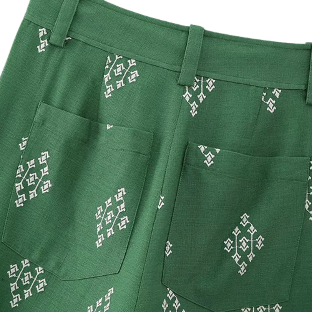 Green boho chic pants with white geometric patterns and two back pockets, shown from the waist down. The fabric has a subtle texture, and these wide-leg trousers feature handy belt loops for a relaxed yet stylish look.