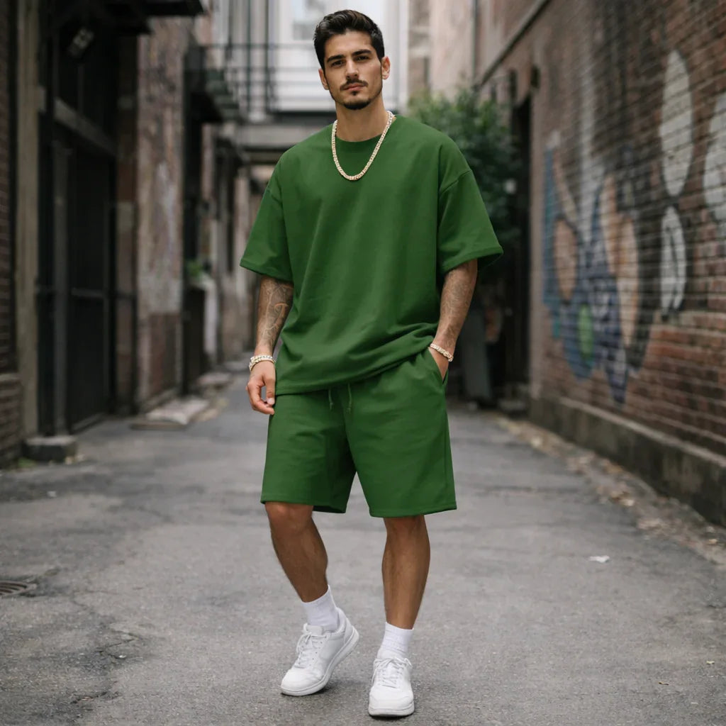 Man wearing green oversized T-shirt and shorts from Rovelli, standing in urban alley