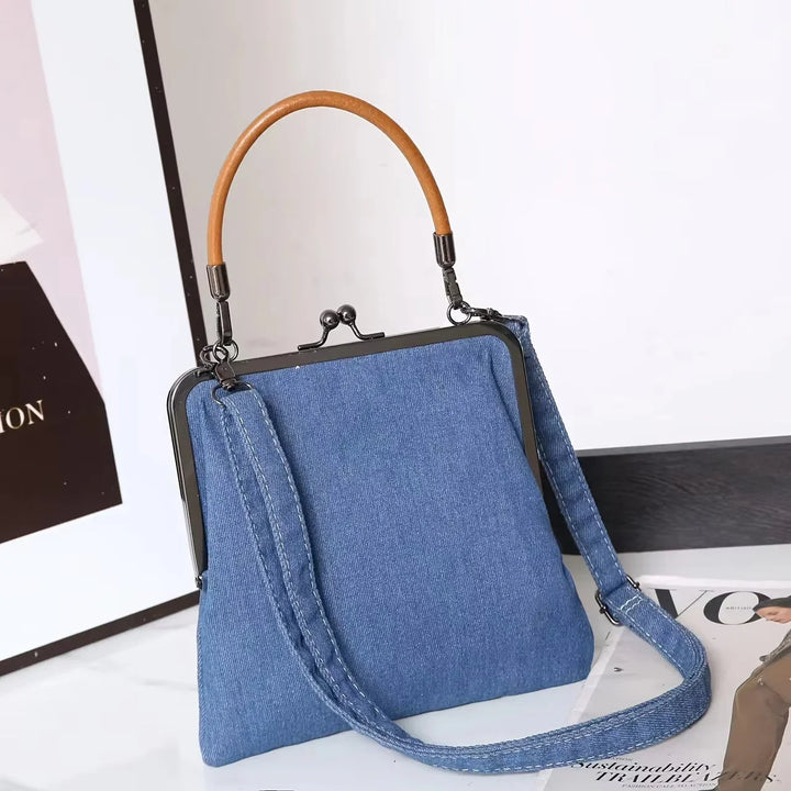 Rovelli blue denim handbag with wooden handle and crossbody strap on white table