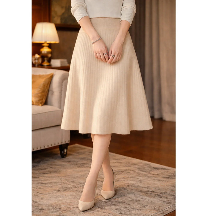 Woman in beige knit midi skirt and heels standing in elegant living room, Rovelli fashion